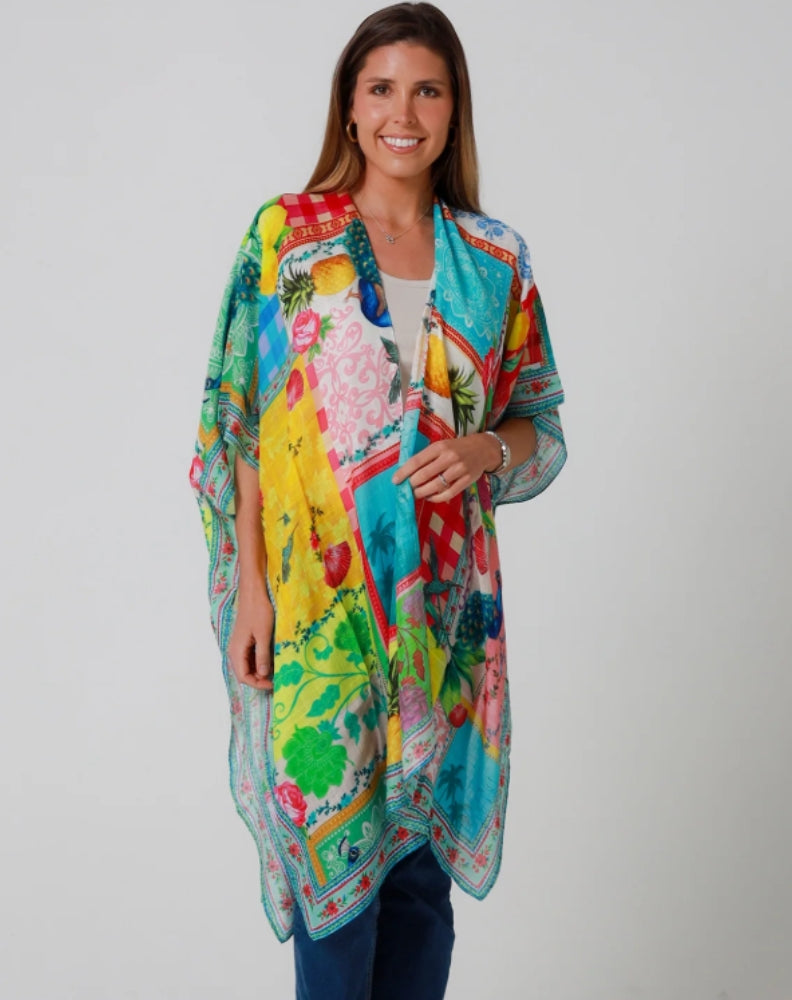 Woman wearing a colourful holiday vibe kimono against a plain background