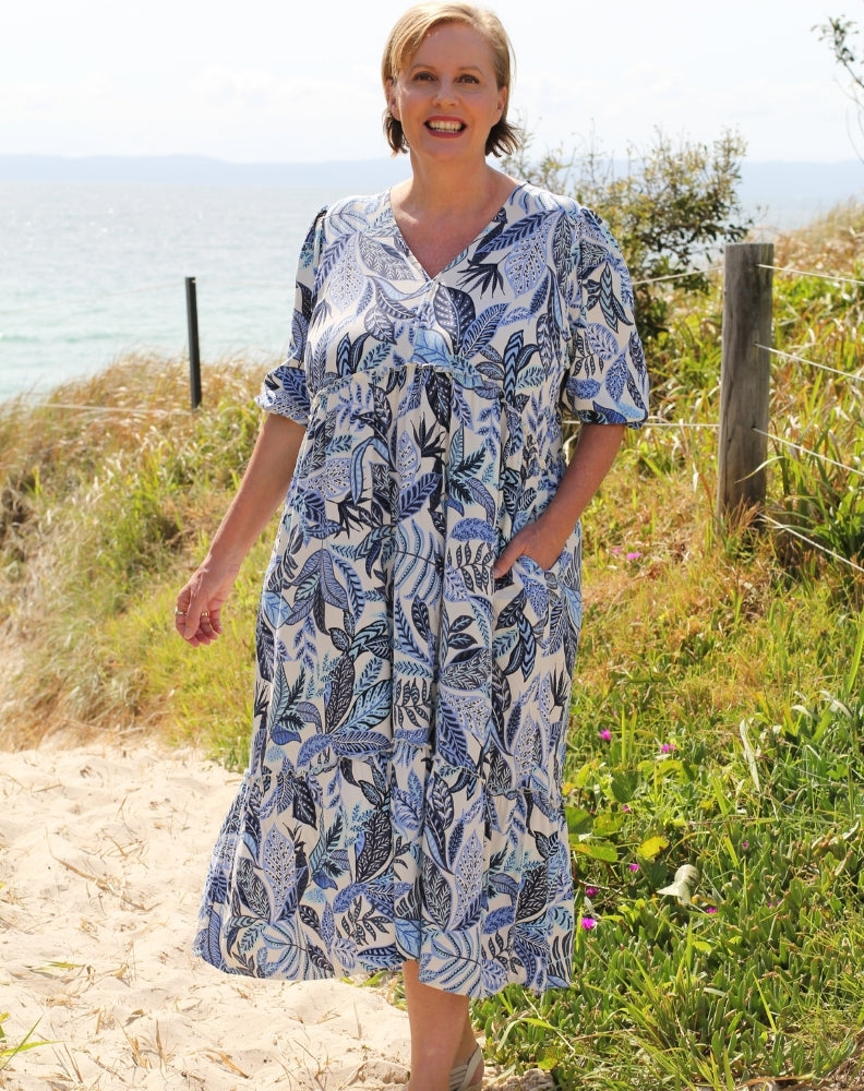 boho midi dress by miss seafari in blue leaves print showing pockets whil walking at beach