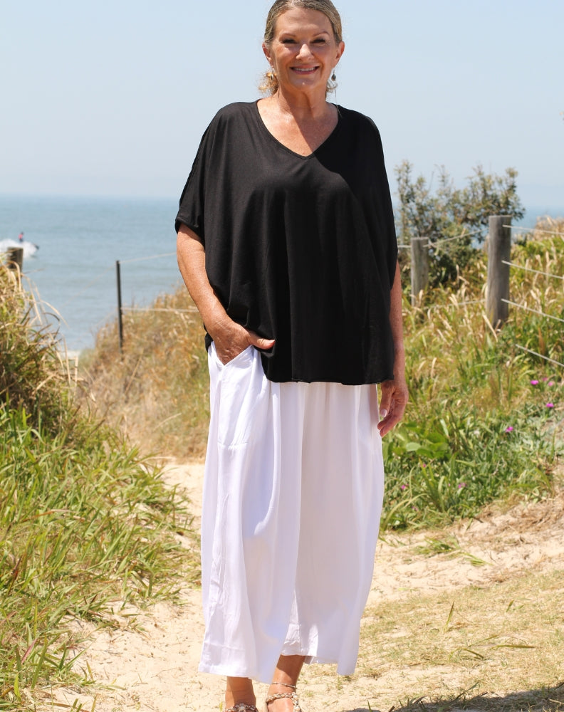 cold shoulder top in black modal worn tucked out of resort pant showing flattering curved hem