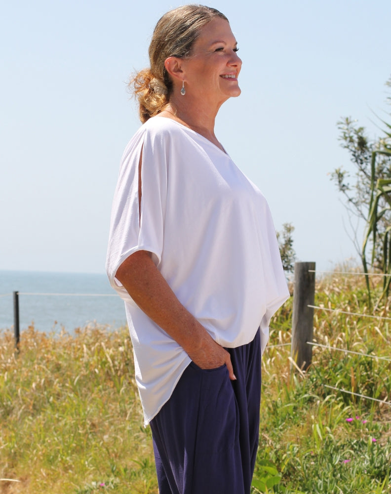 cold shoulder top in white modal side view showing shoulder detail and curved hem