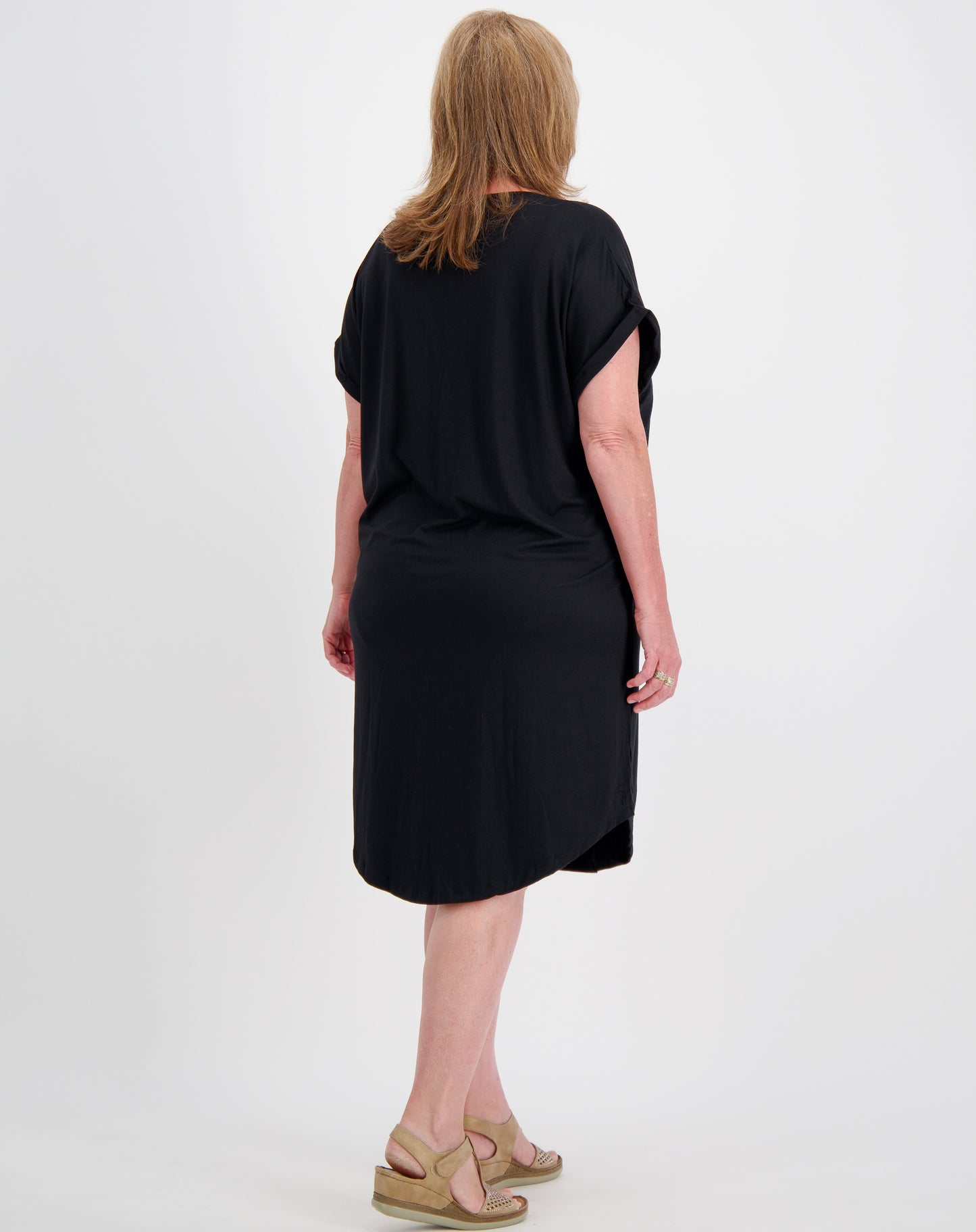 Woman wearing a black dress showing back of dress with curved hem