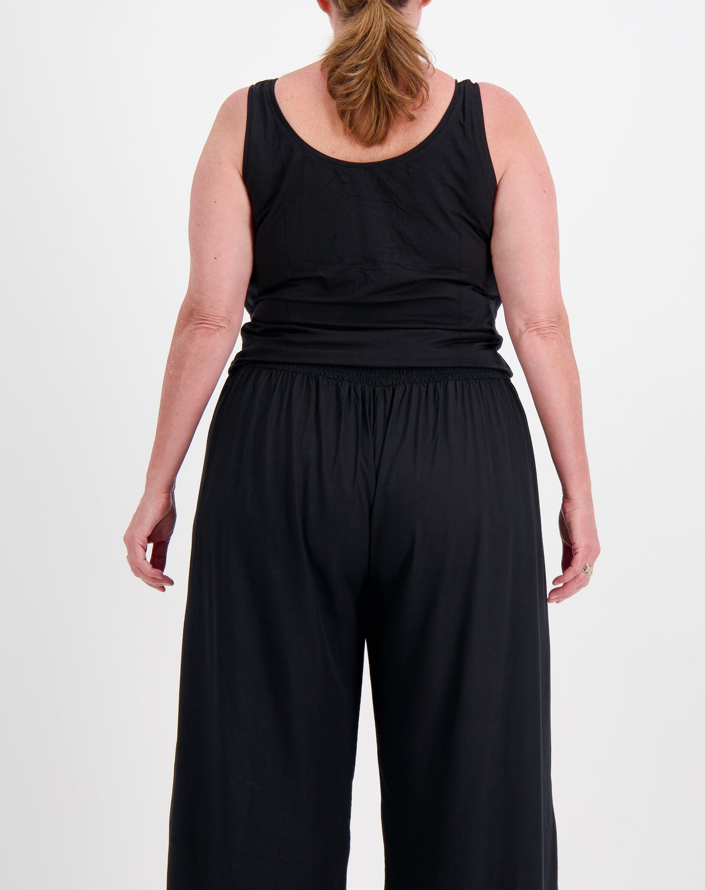 Person wearing a miss seafari black sleeveless layer top and wide-leg pants on a white background
