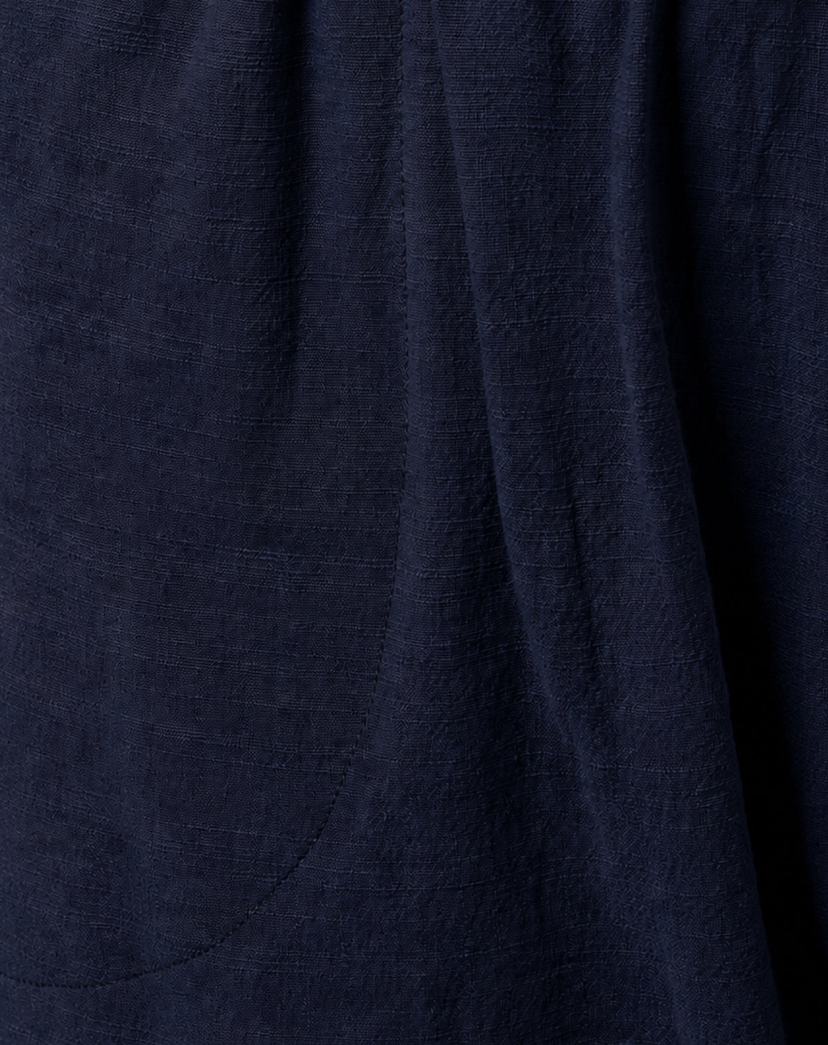 Close-up of dark navy blue textured cotton fabric with soft folds and a subtle woven linen-like surface.