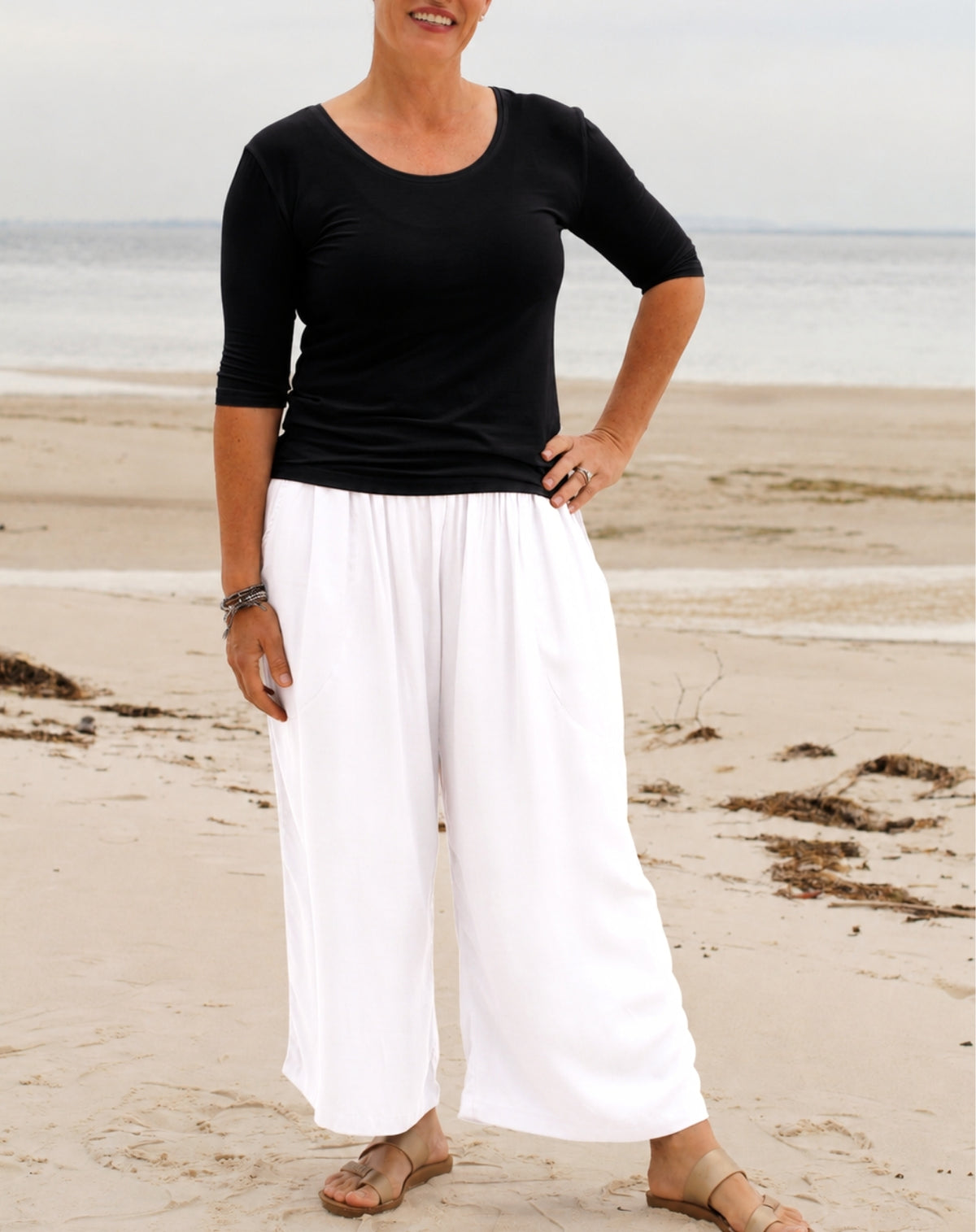 everyday pant in white worn on holidays at beach with black scoop tee and sandals