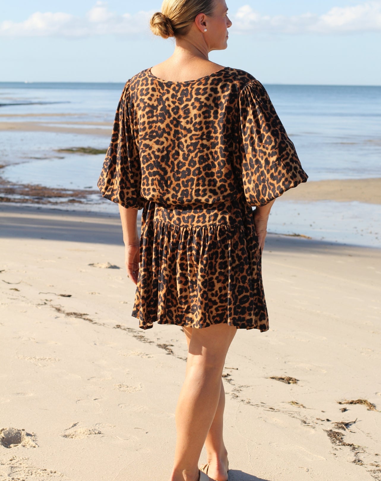 Woman wearing a beach boho leopard print dress looking out to the ocean