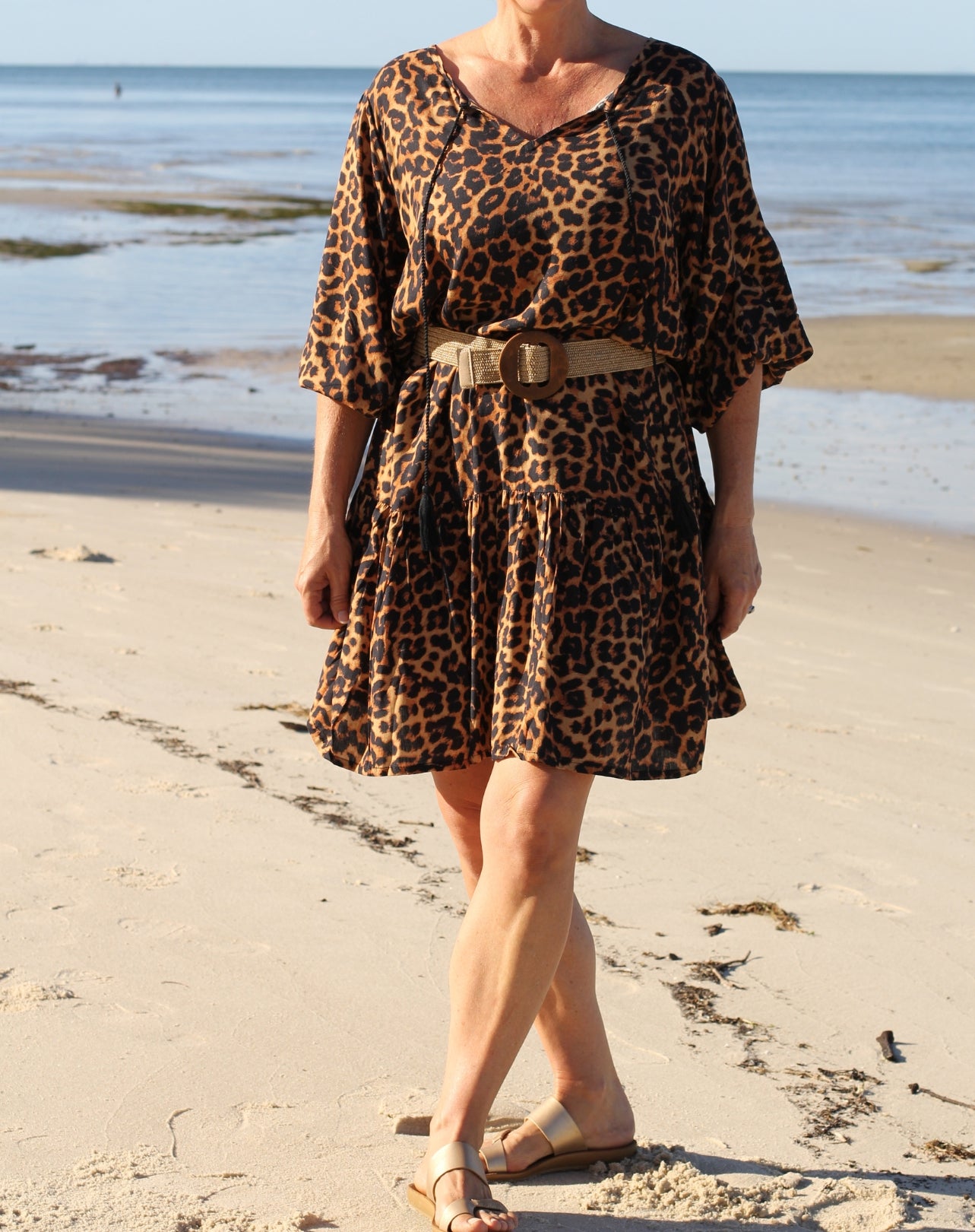 Person wearing a boho style leopard print dress on a beach