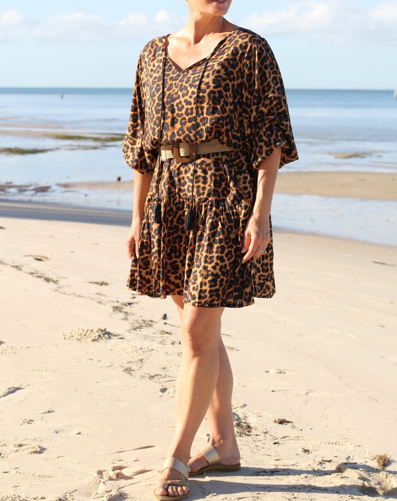 Person wearing ab each boho leopard print dress standing on the sand