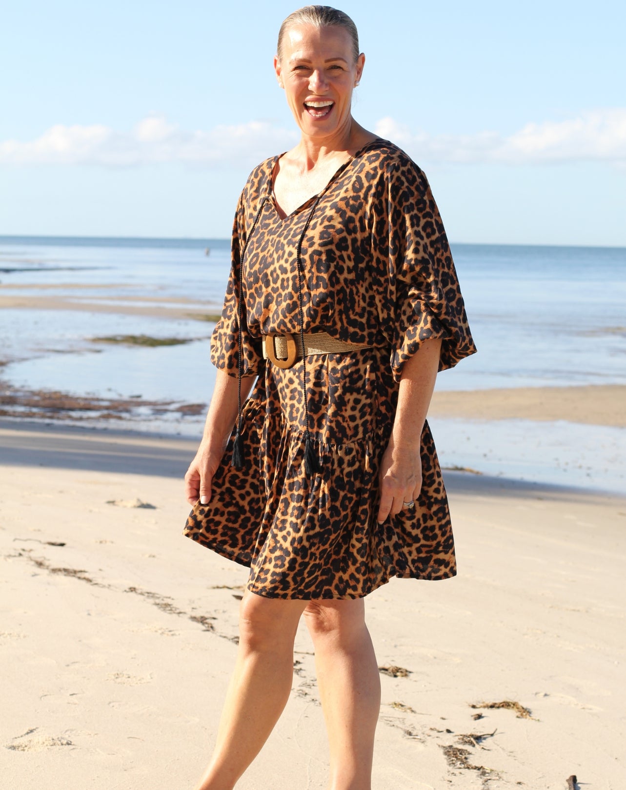 Woman wearing a boho style leopard print dress on a beach
