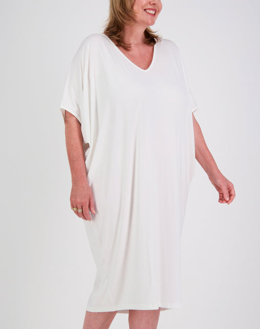 Woman wearing a white comfort dress dress below knee against a plain background