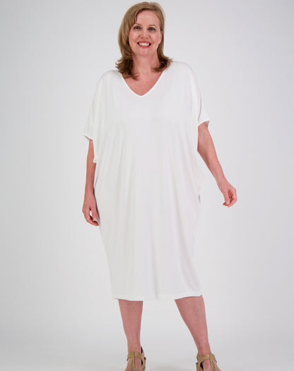 Woman wearing a white modal dress with batwing style on a plain background