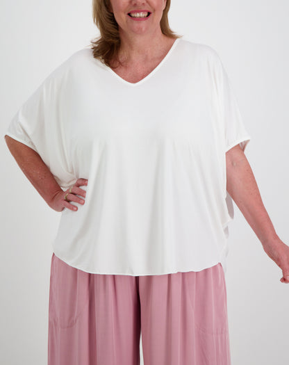 Woman wearing a white modal comfort top and pink everyday pants by miss seafari on a plain background