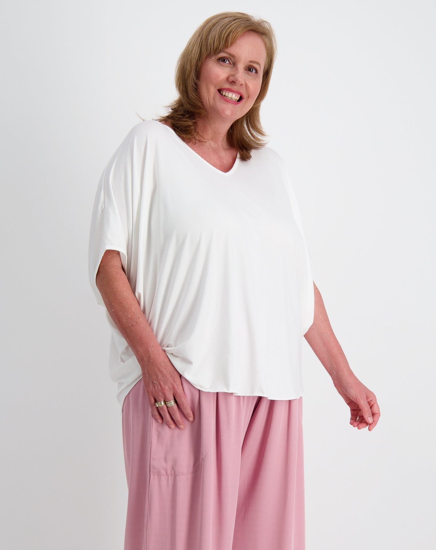 Woman wearing a white modal top and pink rayon twill everyday pants on a white background