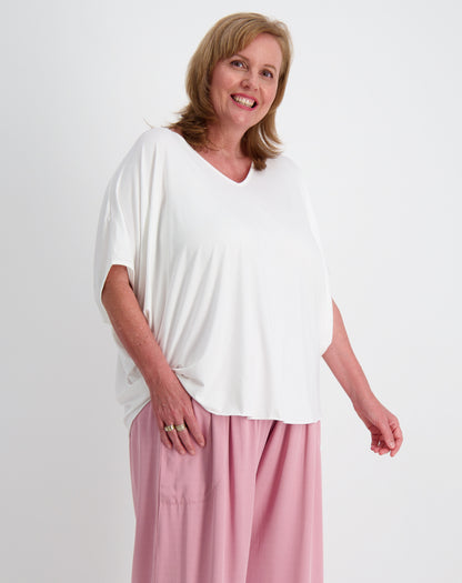 Woman wearing a white modal top and pink rayon twill everyday pants on a white background