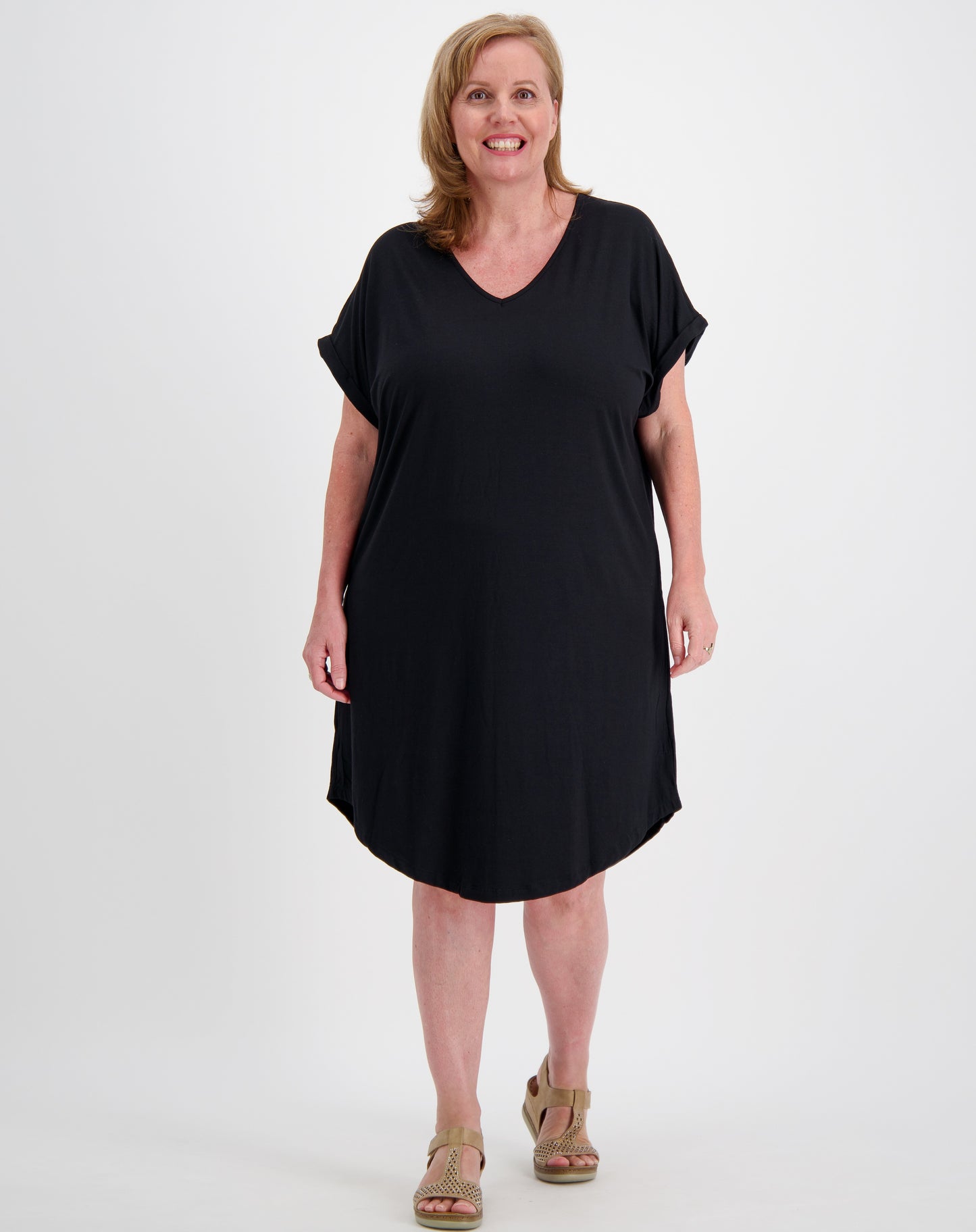 Woman wearing a v neck black curved hem tee dress on a white background