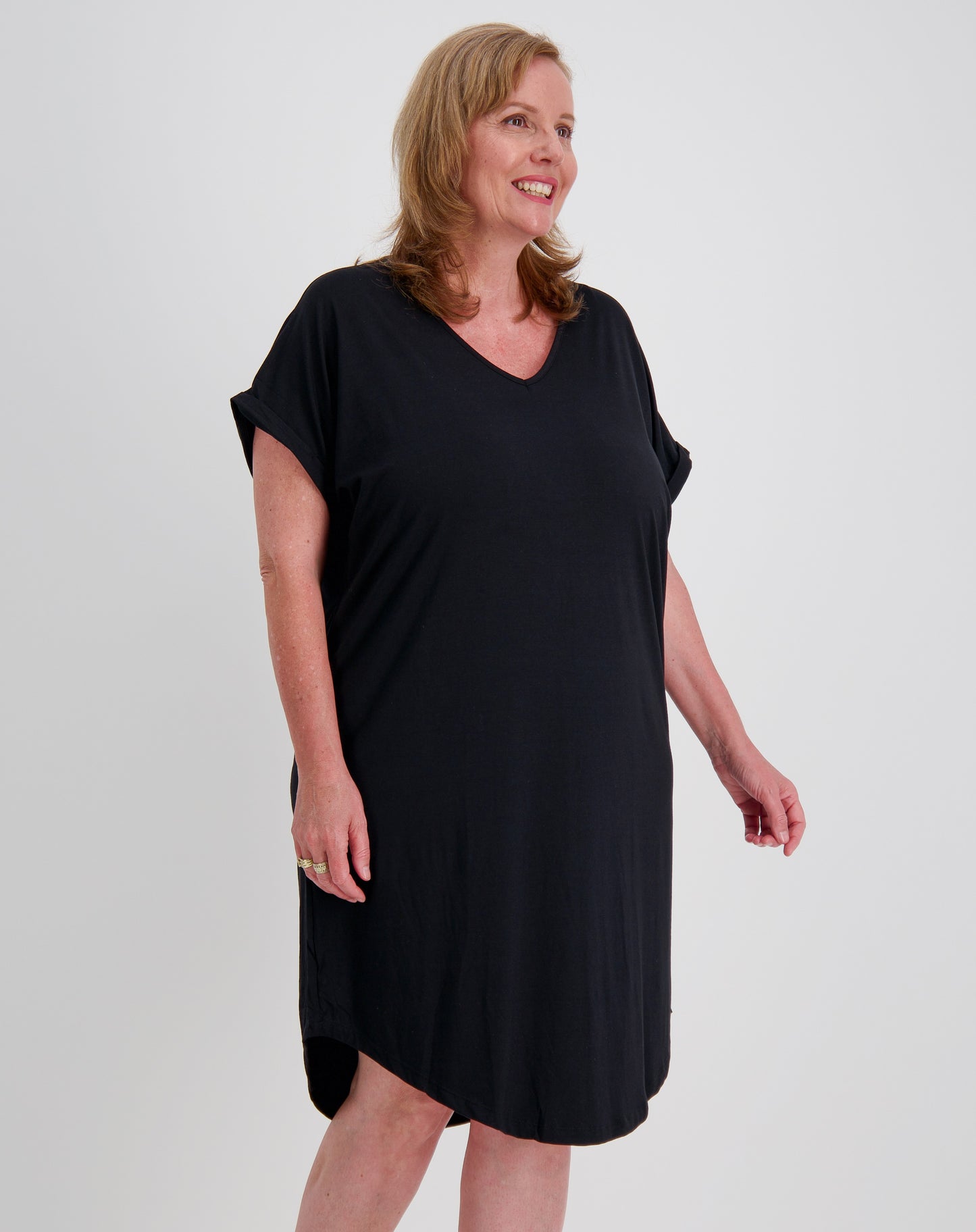 Woman wearing a black curved hem dress against a white background