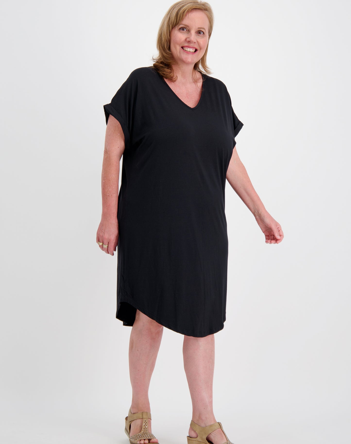 Woman wearing a black curved hem tee dress by miss seafari on a white background