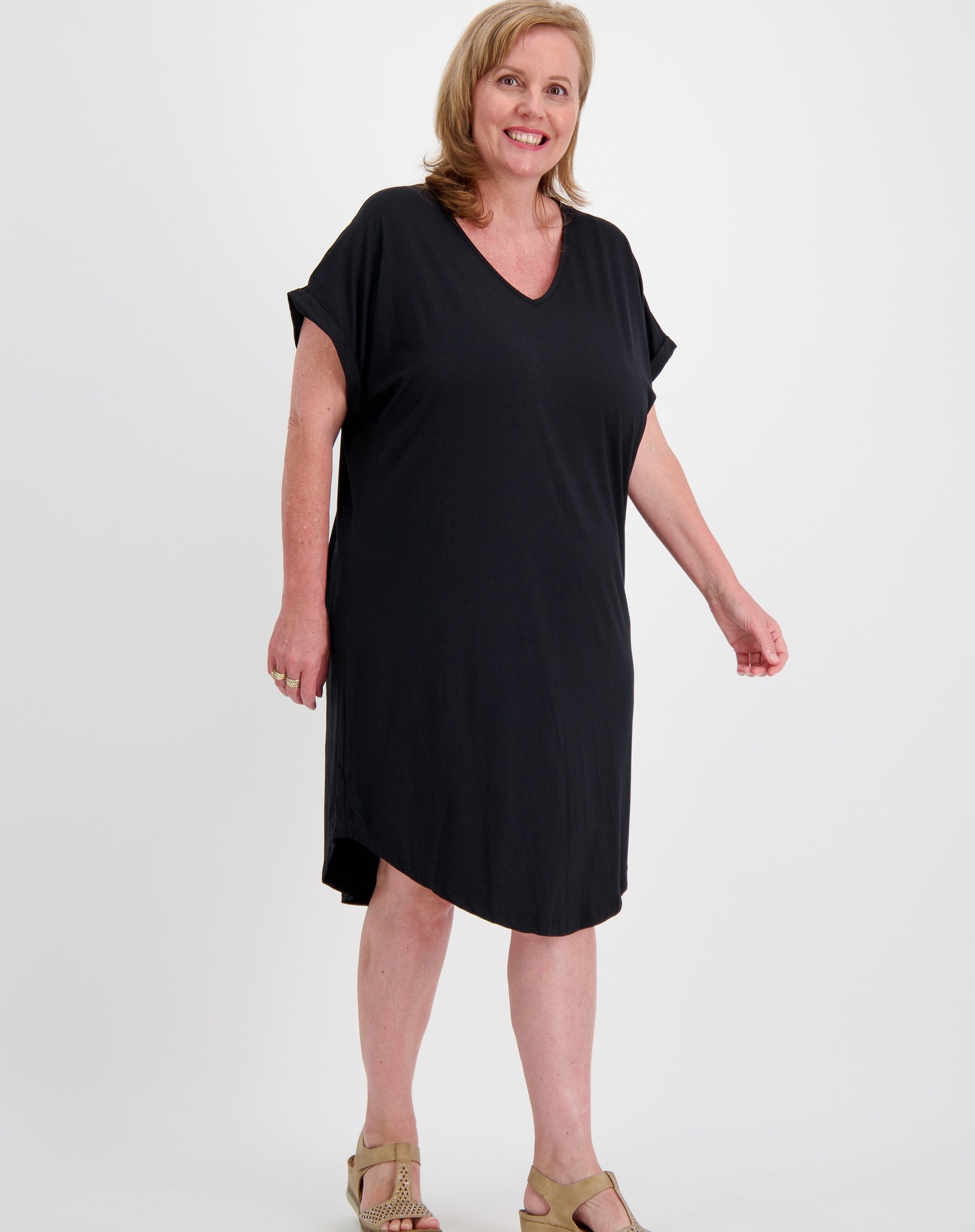 Woman wearing a black curved hem tee dress by miss seafari on a white background
