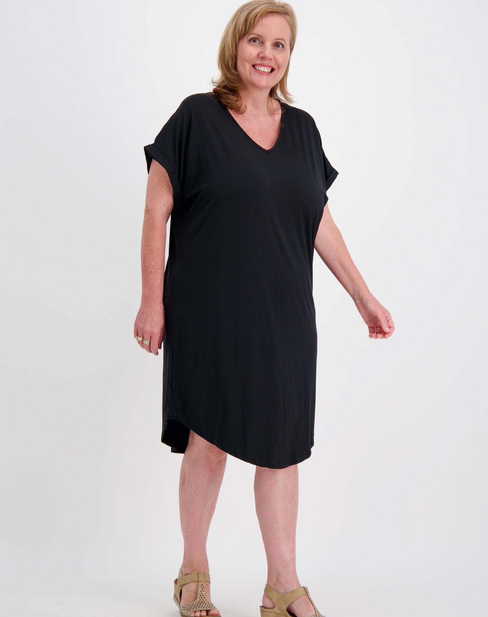 Woman wearing a black curved hem tee dress by miss seafari on a white background