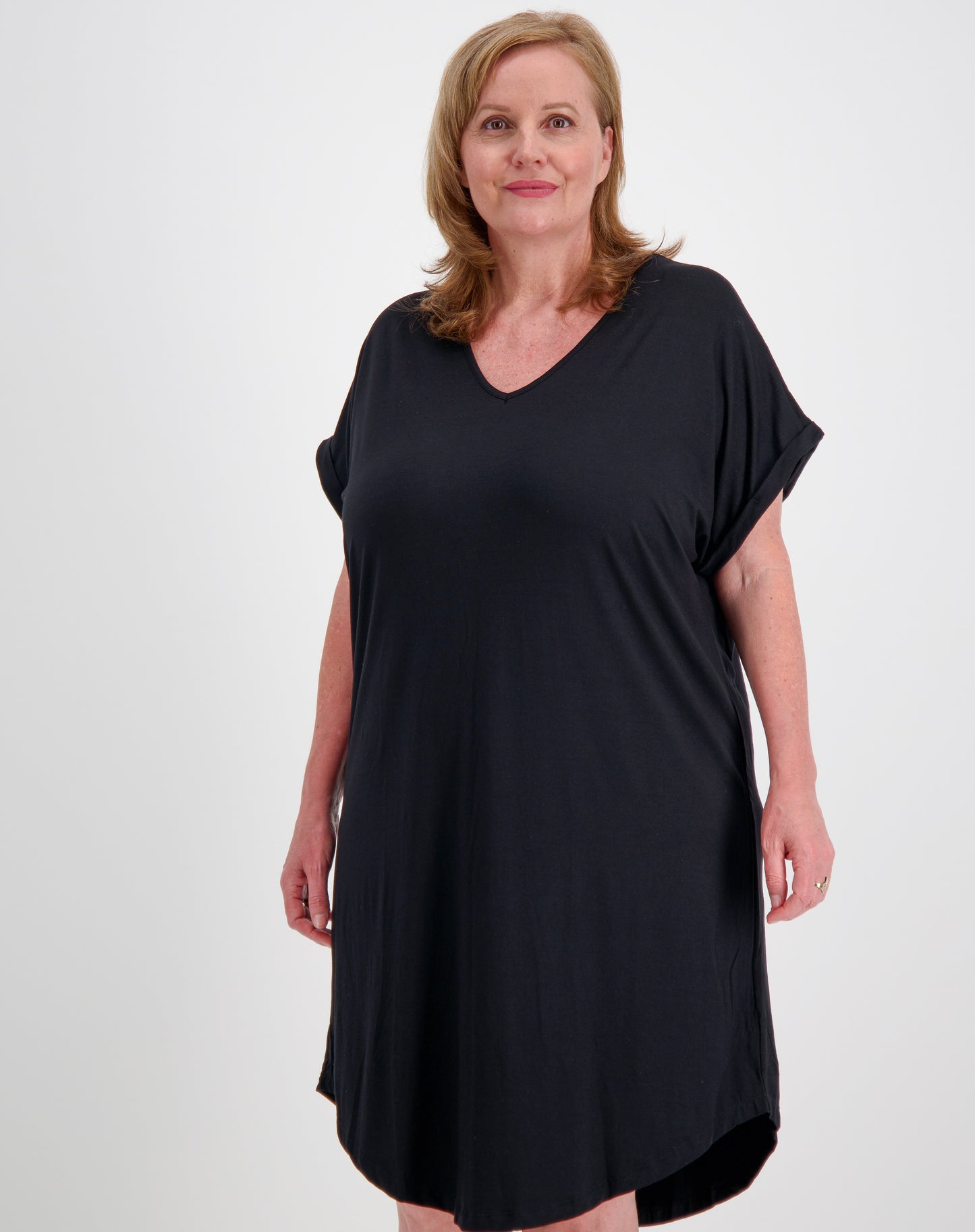 mature woman wearing a black curved hem tee dress in modal fabric against a white background