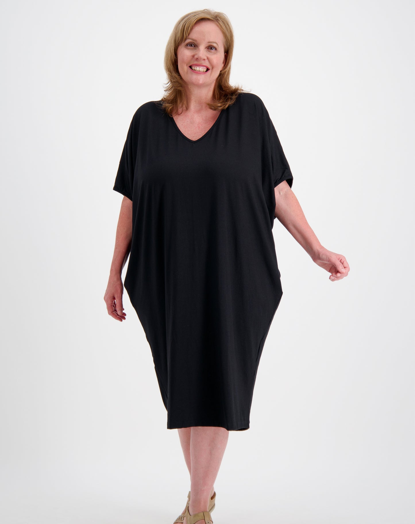Woman wearing a black comfort dress in a photo studio with white background
