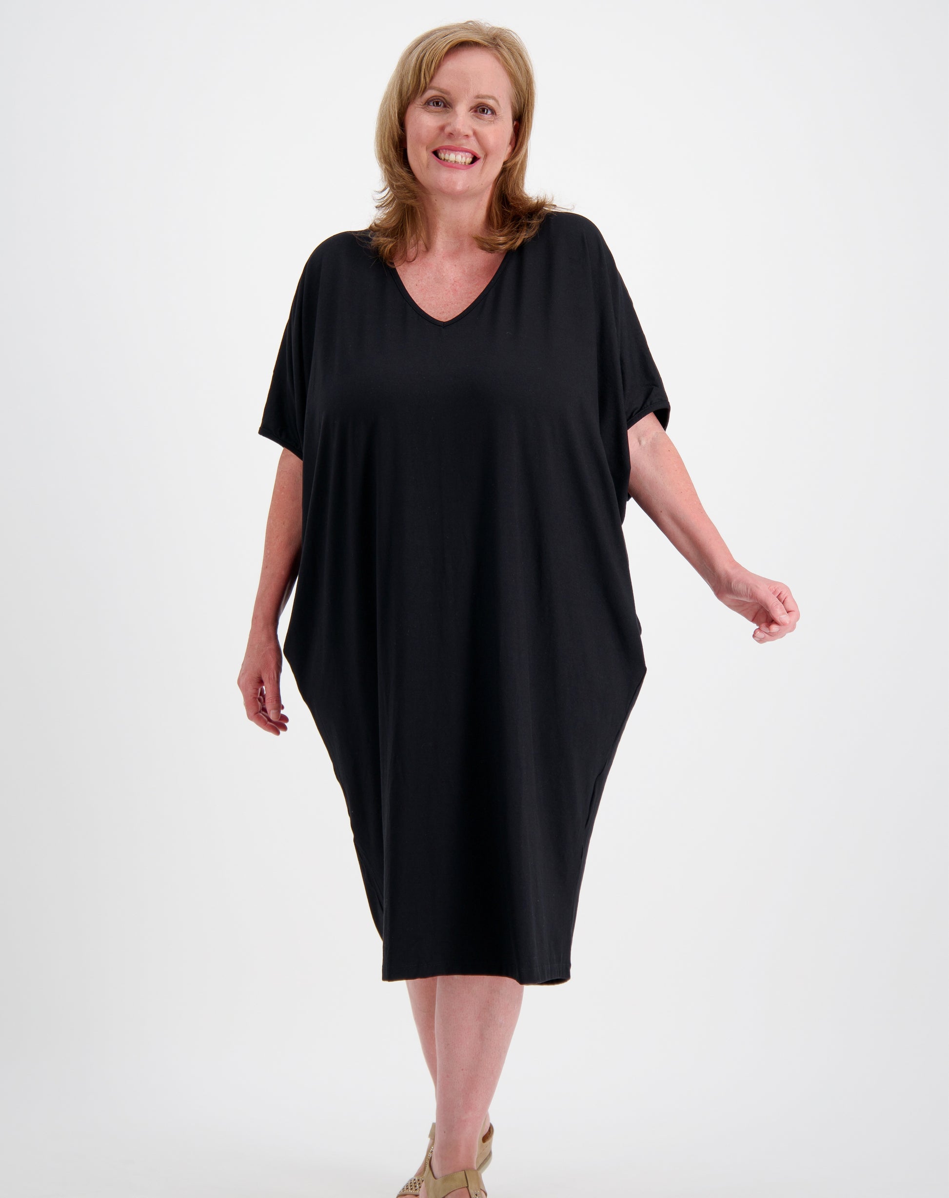 Woman wearing a black comfort dress in a photo studio with white background