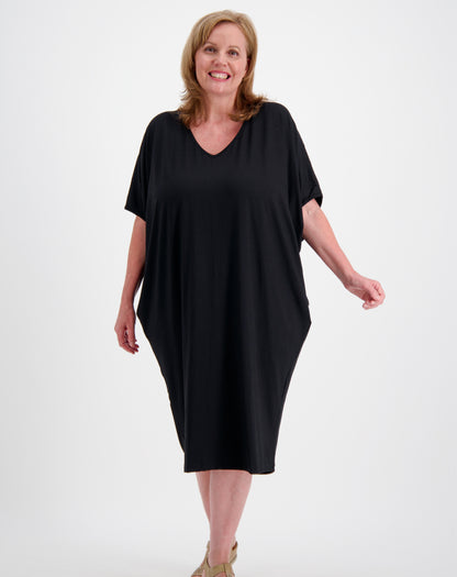 Woman wearing a black comfort dress in a photo studio with white background