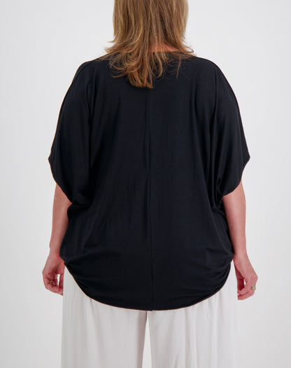 Person wearing a black modal top  with curved hem and white pants on a white background