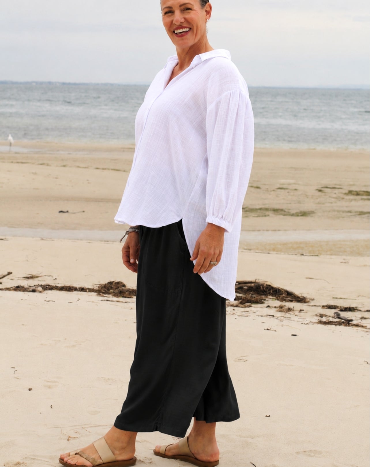 woman at beach wearing wide leg resort style pant and white cotton beach shirt 