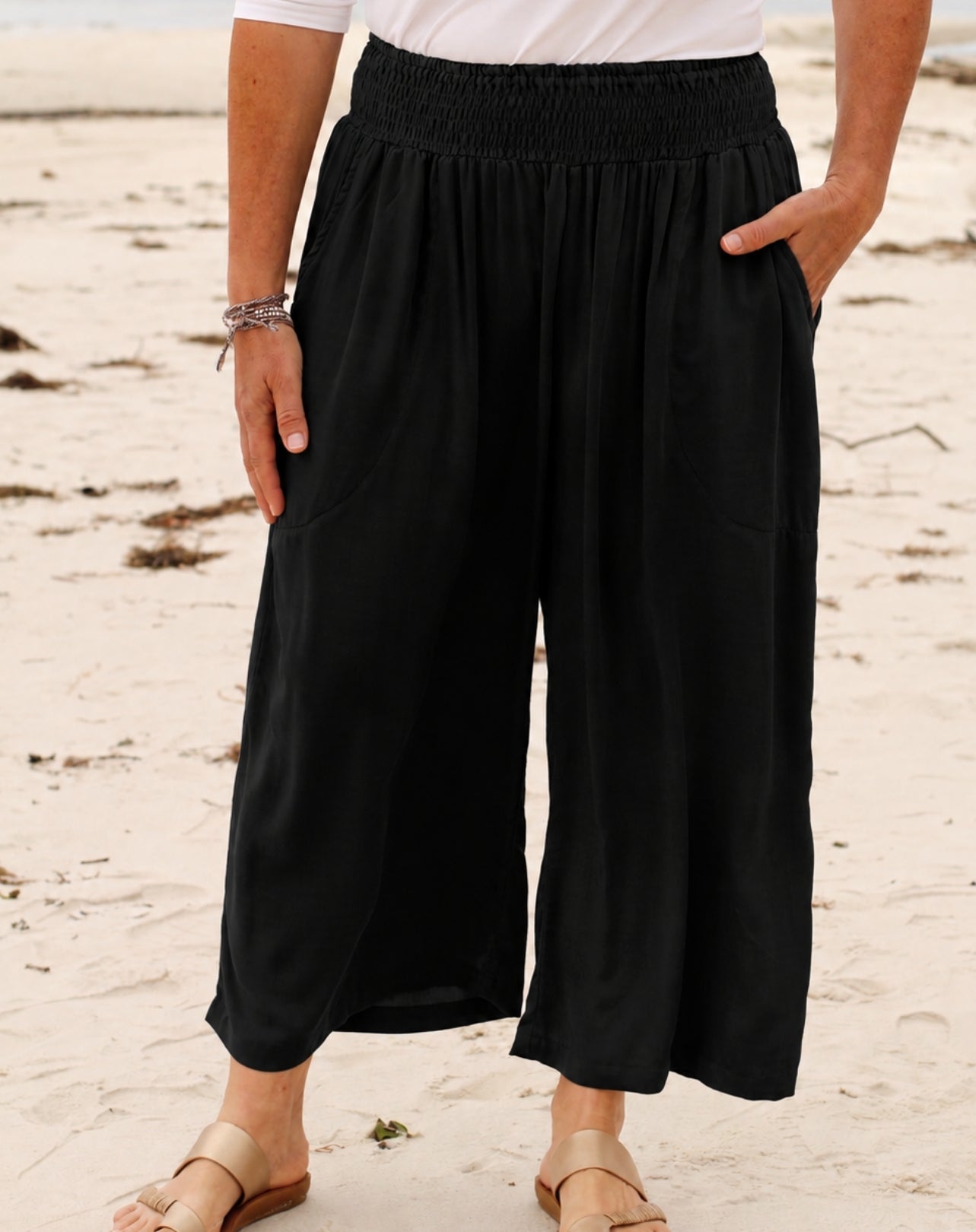 black palazzo style wide leg pant with pockets on woman standing in sand at beach