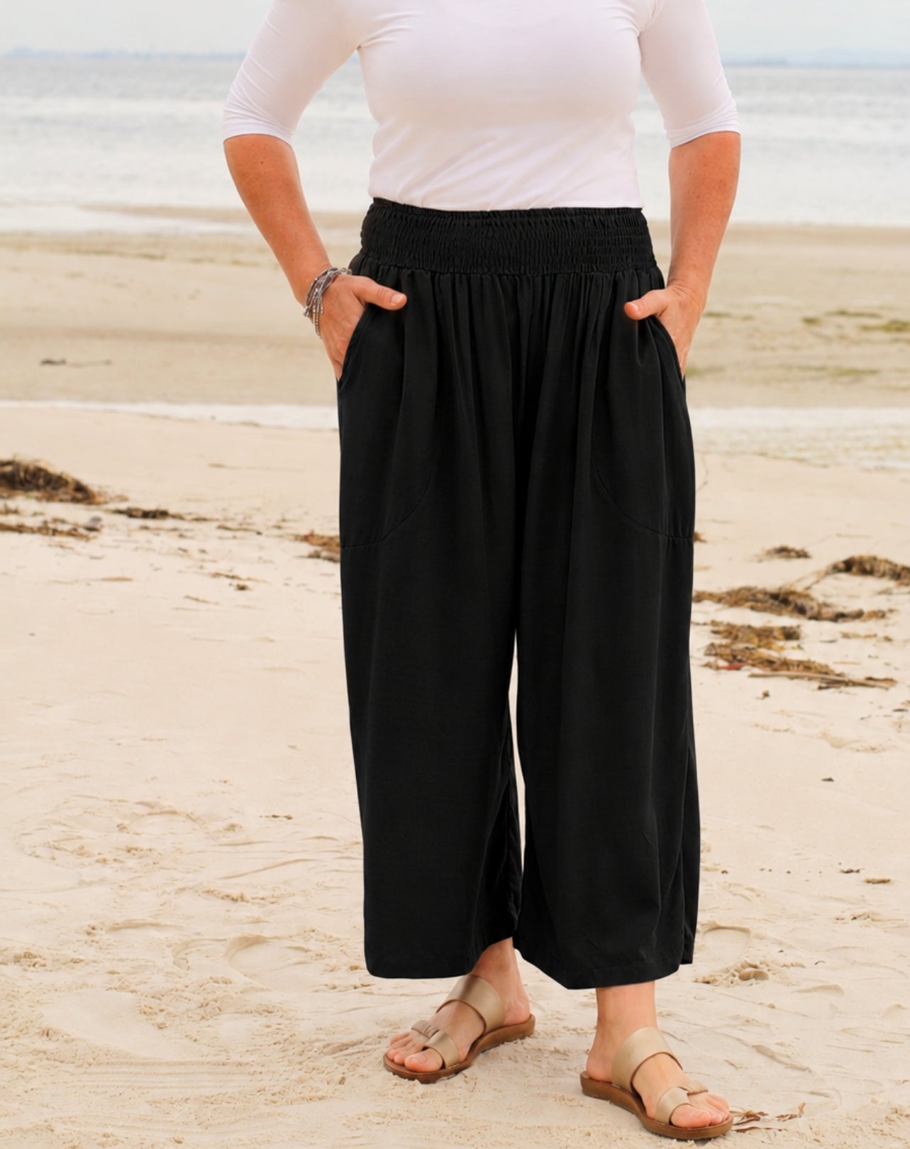 woman wearing 7/8 cropped resort style pant with pockets in black with sandals and white tee