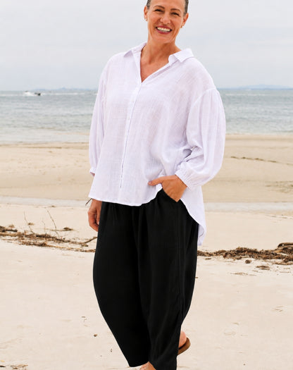woman wearing black wide leg pant and white beach shirt standing on the sand at Bribie island