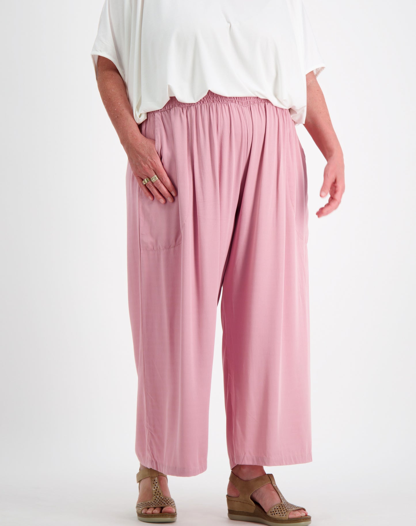 Person wearing a white modal top and pink everyday pants showing pocket size on a white background