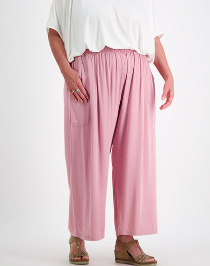 Person wearing a white modal top and pink everyday pants showing pocket size on a white background