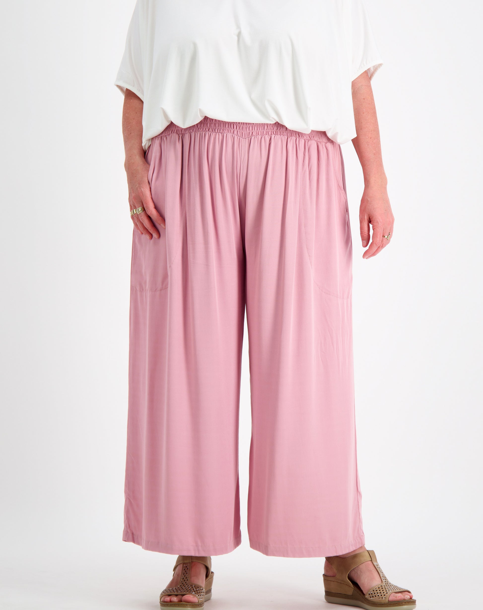 Person wearing everyday pant in blush  and a white  comfort top by miss seafari on a white background