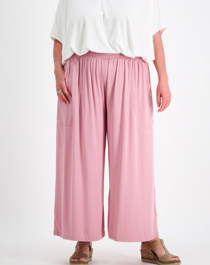 Person wearing everyday pant in blush  and a white  comfort top by miss seafari on a white background