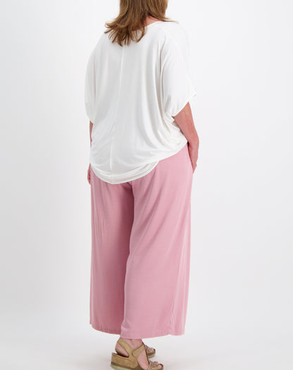 Person wearing a white modal top and everyday pants in a blushed pink on a white background