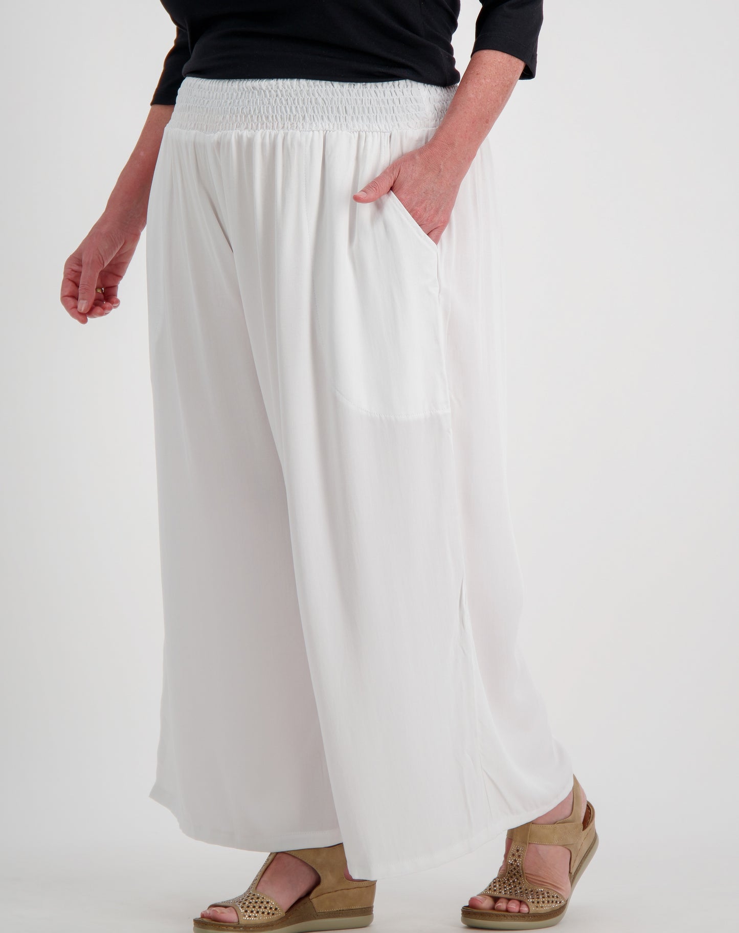 Person wearing white wide-leg pants on a plain background