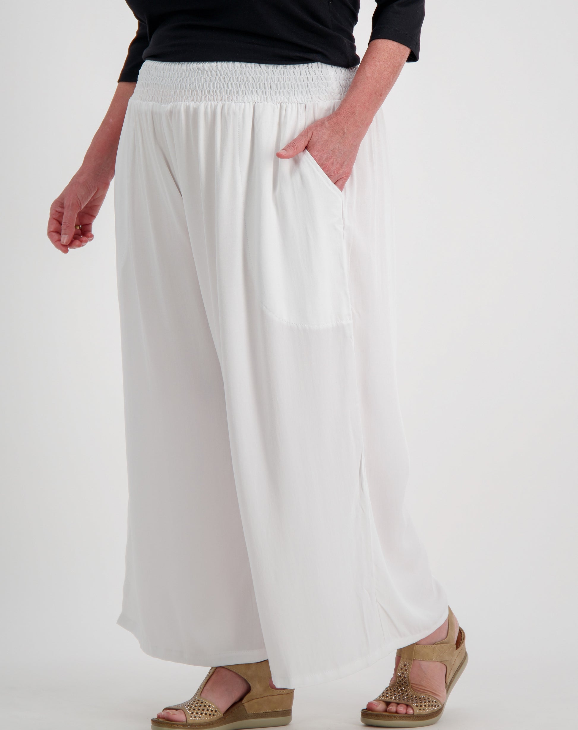 Person wearing white wide-leg pants on a plain background