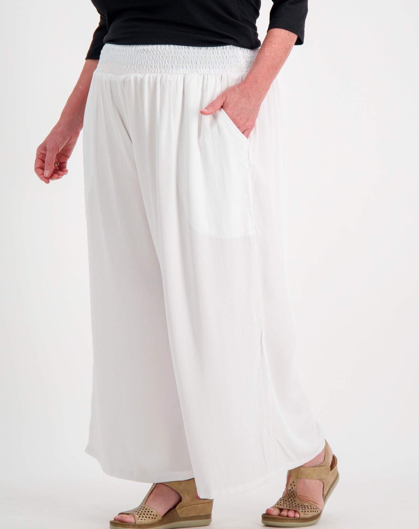 Person wearing white wide-leg pants on a plain background
