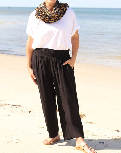 Person wearing a white top and black every day pants on a beach