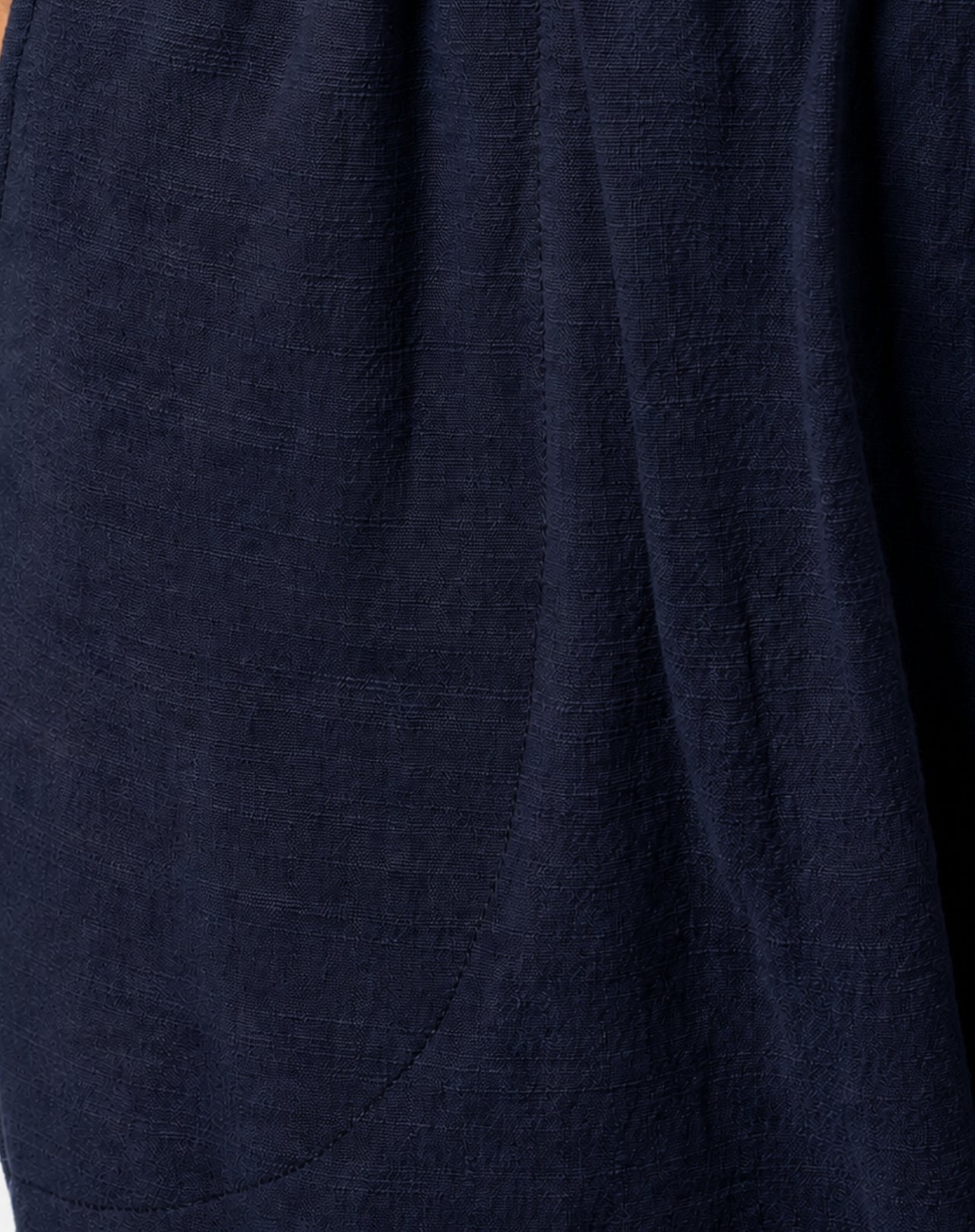 Close-up of dark navy blue textured linen look fabric with soft folds and a curved seam detail.