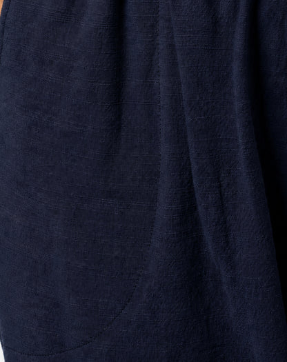 Close-up of dark navy blue textured linen look fabric with soft folds and a curved seam detail.