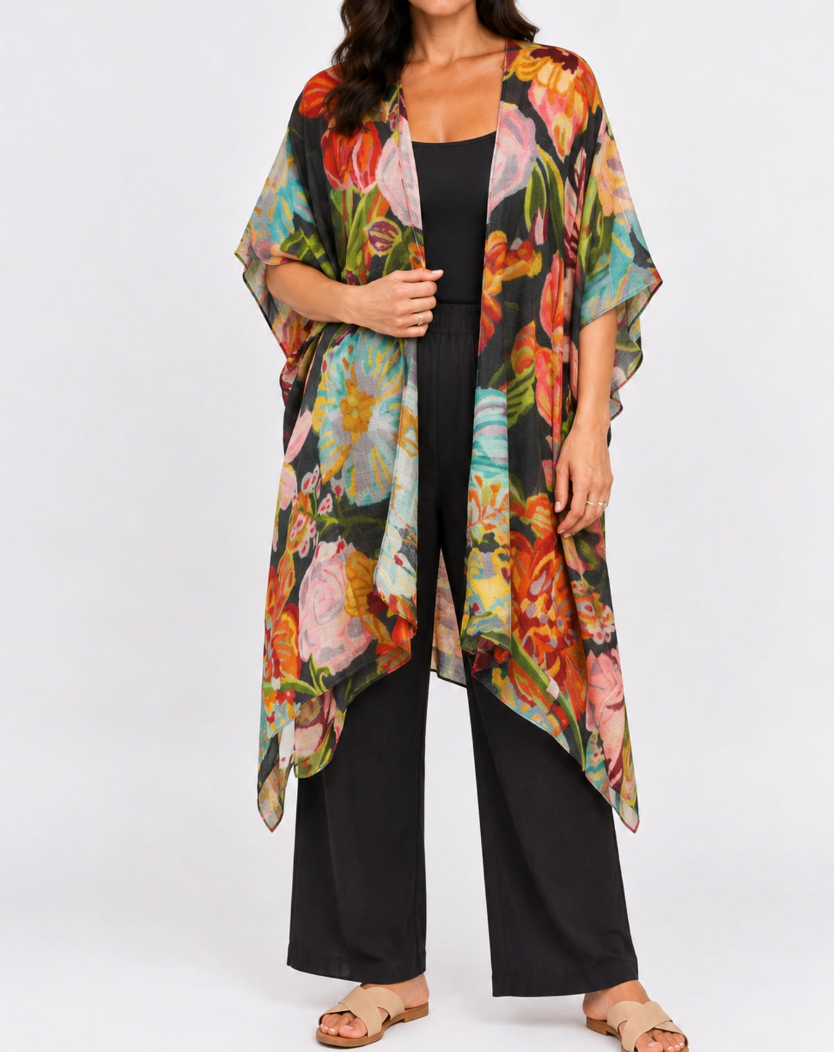 A woman models a lightweight, open-front kimono-style cardigan featuring a vibrant multicolor floral print over a solid black outfit, set against a plain light gray studio background.