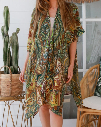 size 10 woman wearing green paisley kimono in a room with a cactus plant and wicker chair.