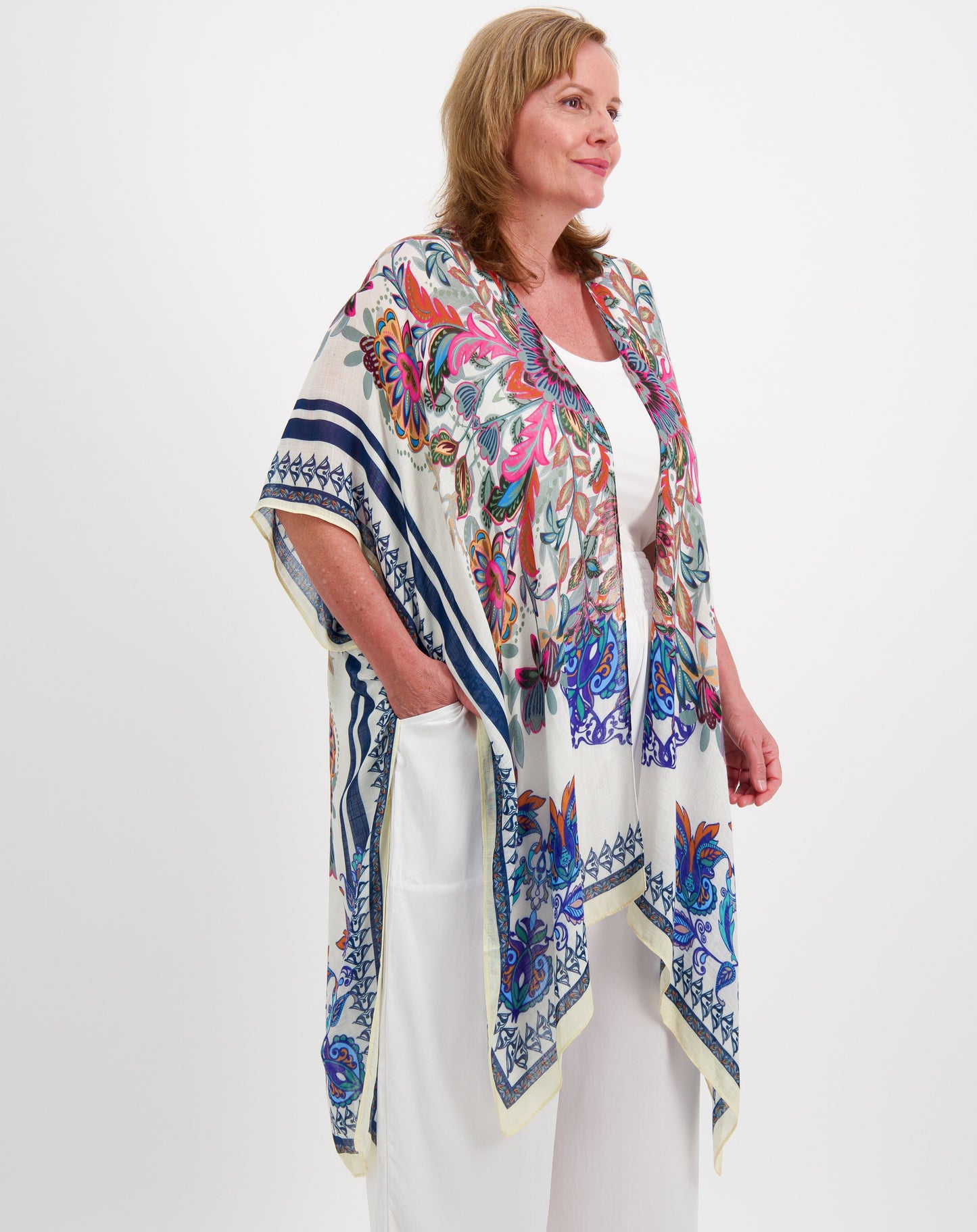 Woman wearing a colorful patterned kimono jacket in boho print in pink and blue on a white background