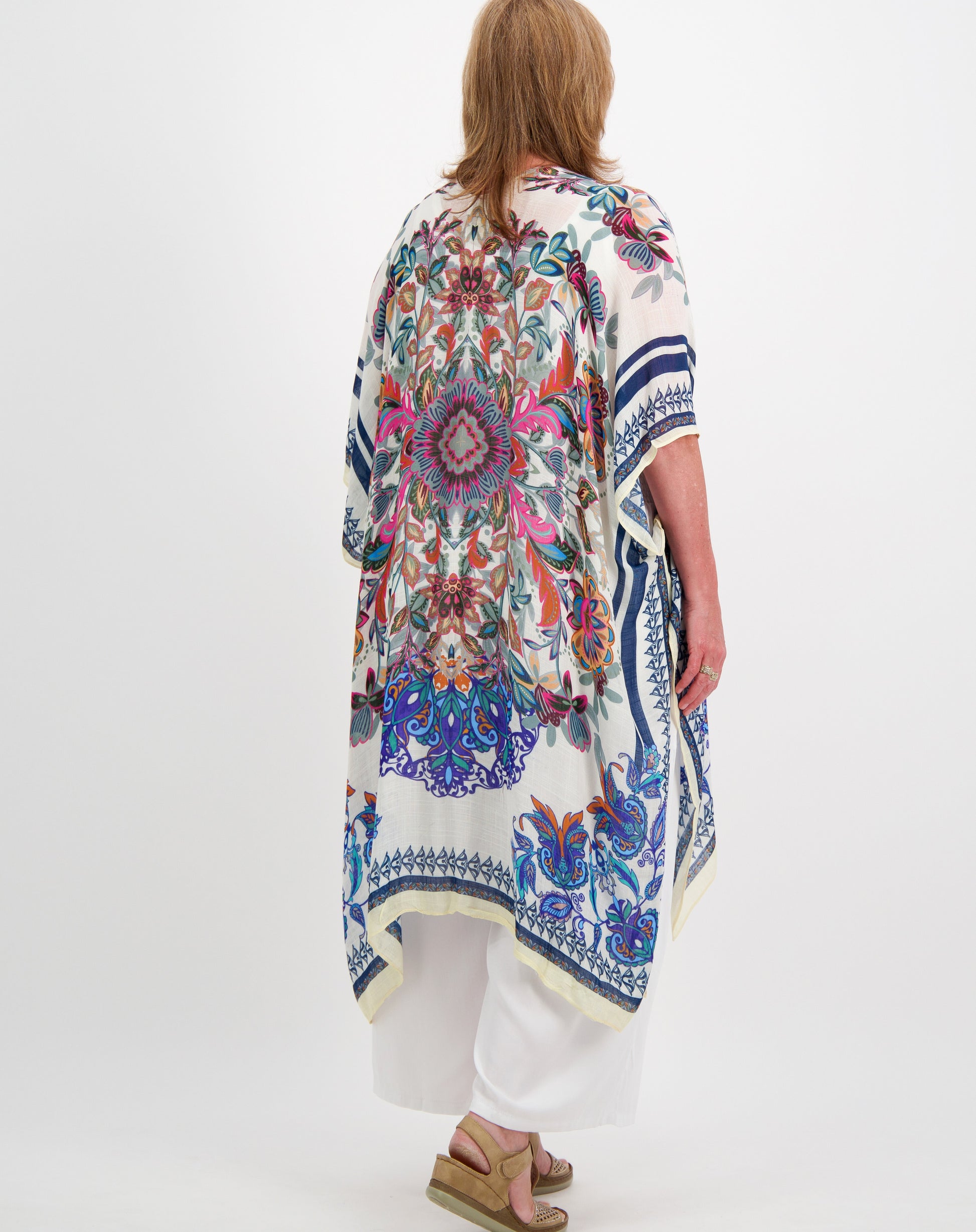 Woman wearing a kimono-style jacket with boho design on a white background