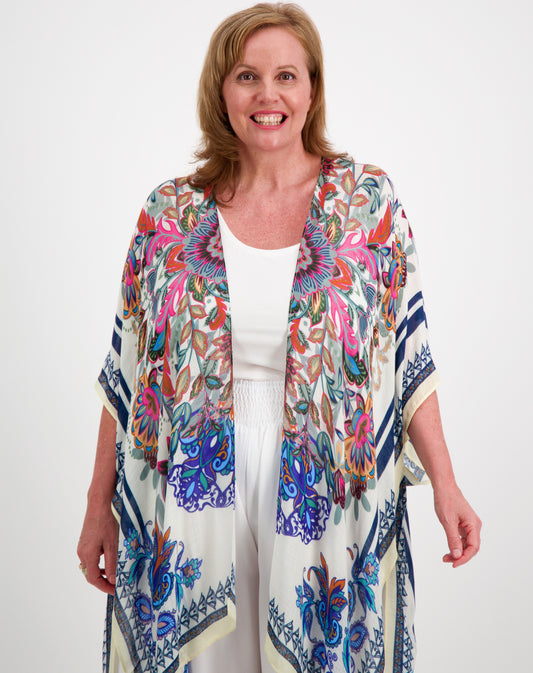 Woman wearing a boho kimono in pink and blue over a white outfit on a white background