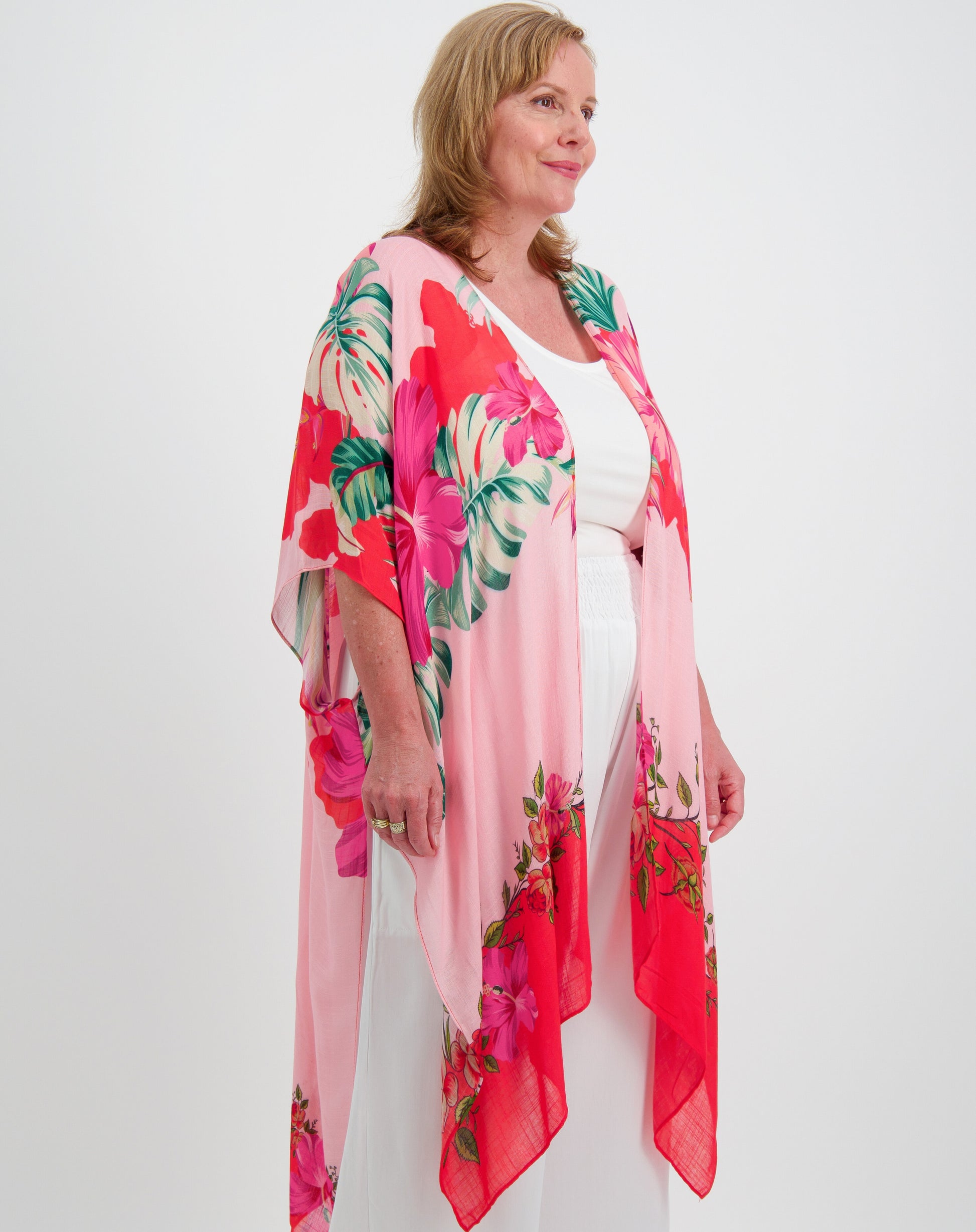 Woman wearing a pink toucan kimono with modal layer tank and white everyday pant against a white background