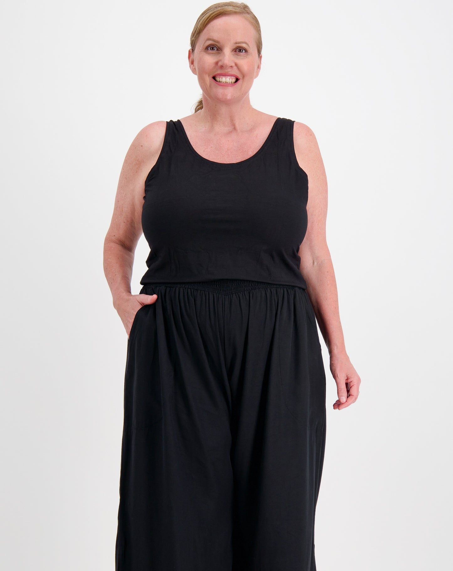 Curve woman wearing a black sleeveless tank in modal and black pants on a white background