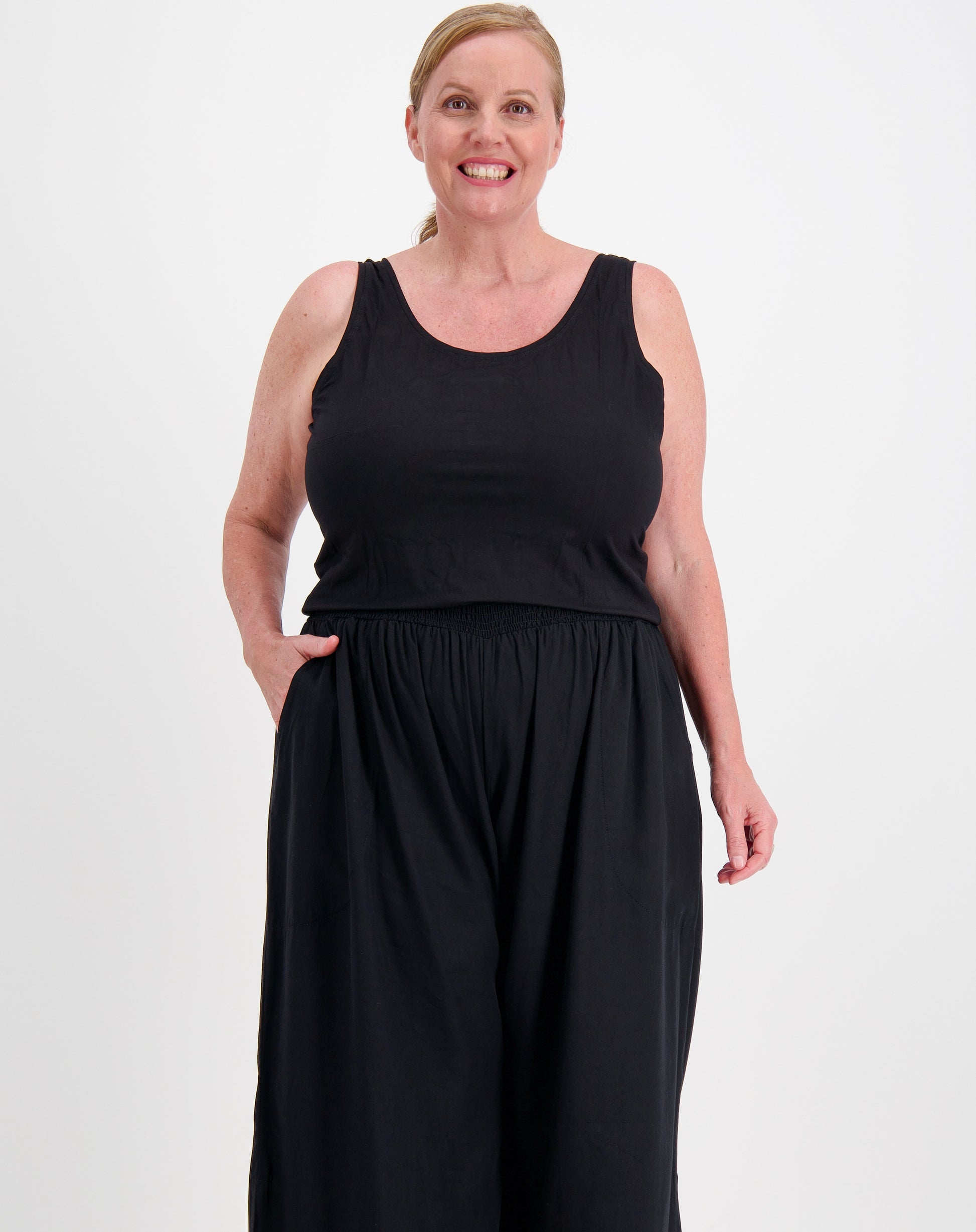 Curve woman wearing a black sleeveless tank in modal and black pants on a white background